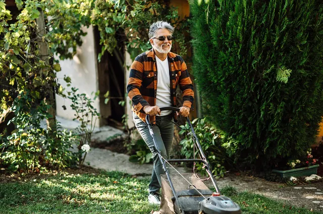 Landscaper mowing crisp stripes into a lush green residential lawn